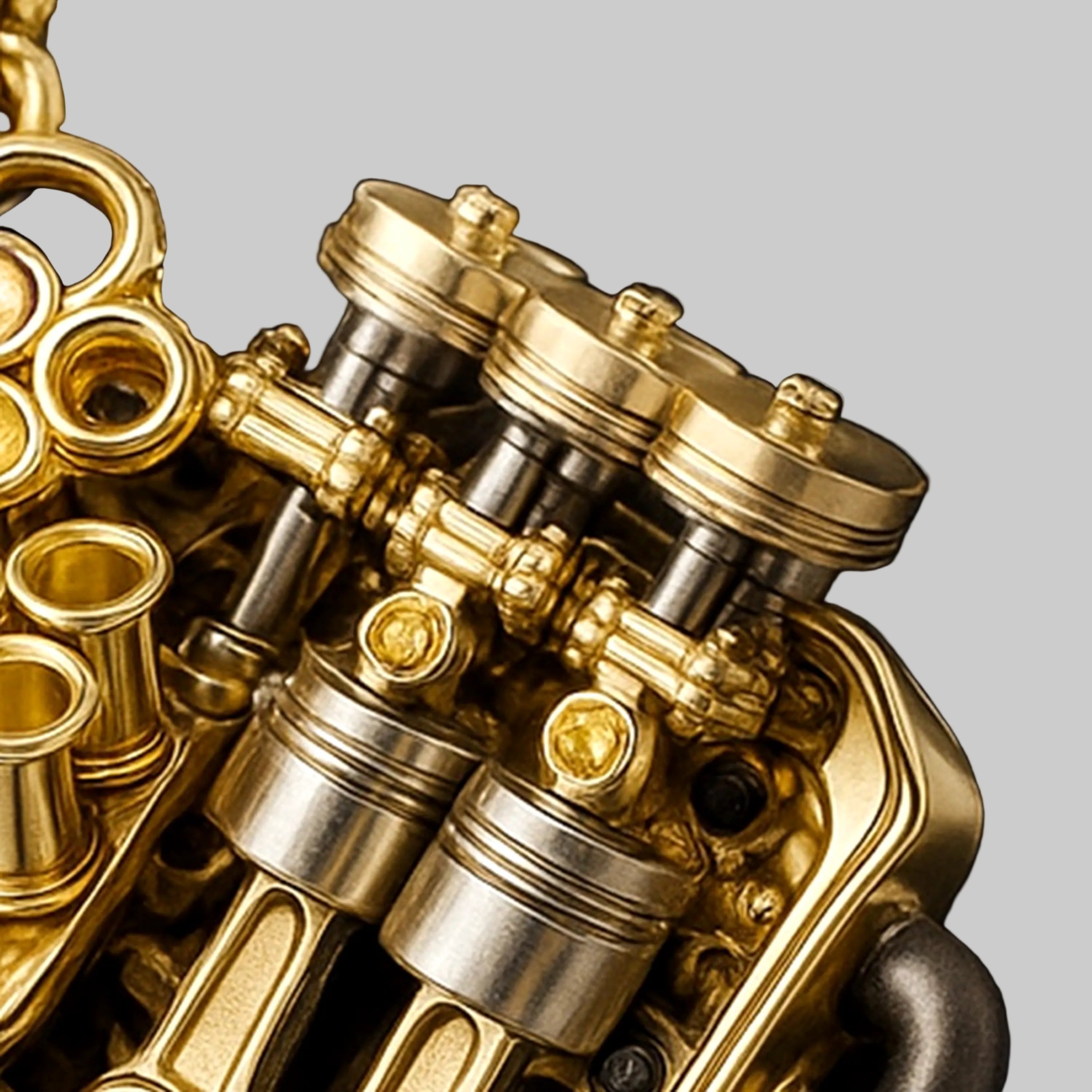 Macro of V12 engine–inspired pendant in 18K yellow gold with twin steel-tone pistons and rocker assembly.