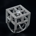 Redbutan Architectural white-gold cube lattice ring with pavé diamond rails, baguette windows, and a floating kite-cut diamond apex on dark background